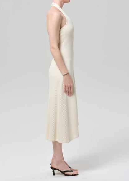 Woman wearing a cream halter neck dress on a plain background