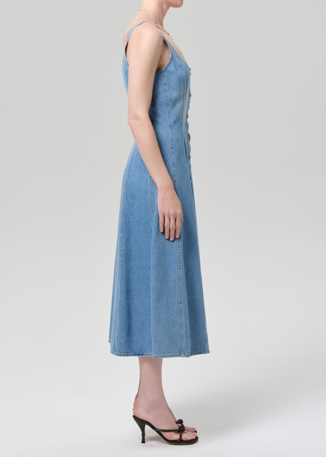 Woman wearing a blue denim dress on a plain background