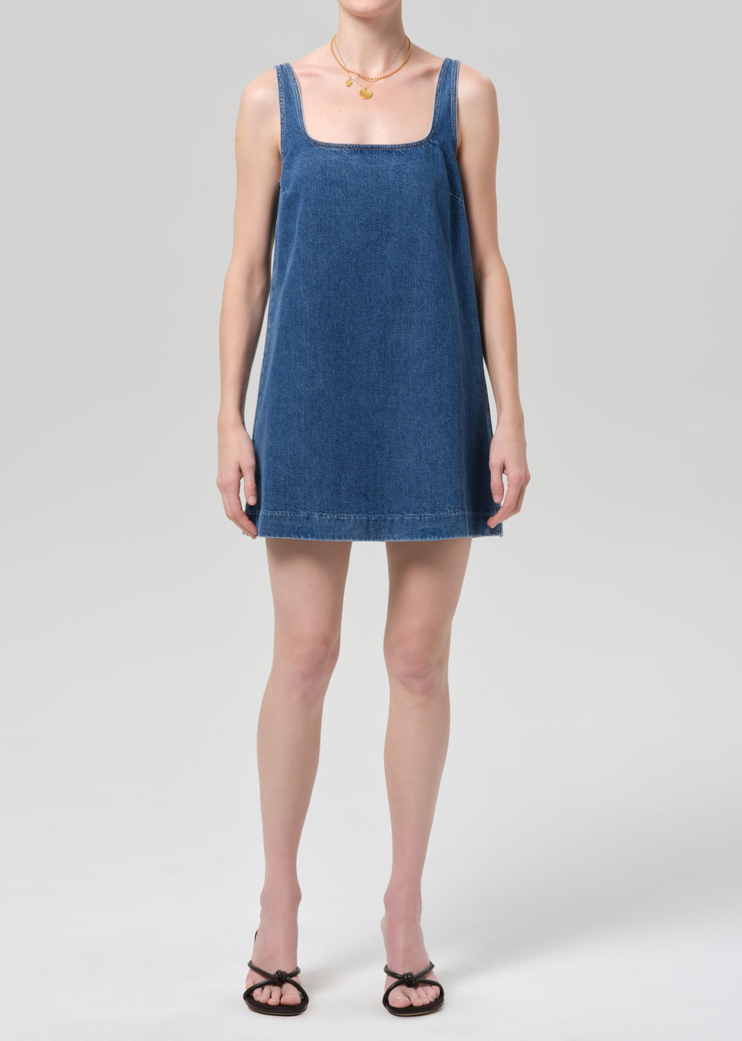Woman wearing a blue denim dress on a plain background