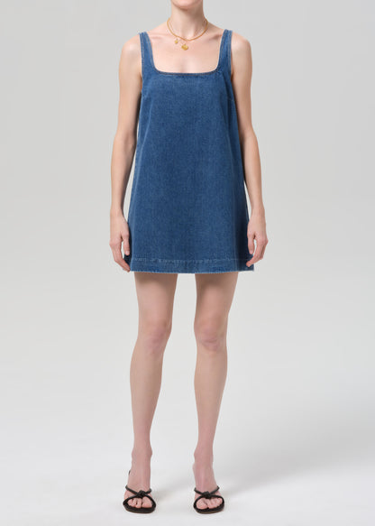 Woman wearing a blue denim dress on a plain background