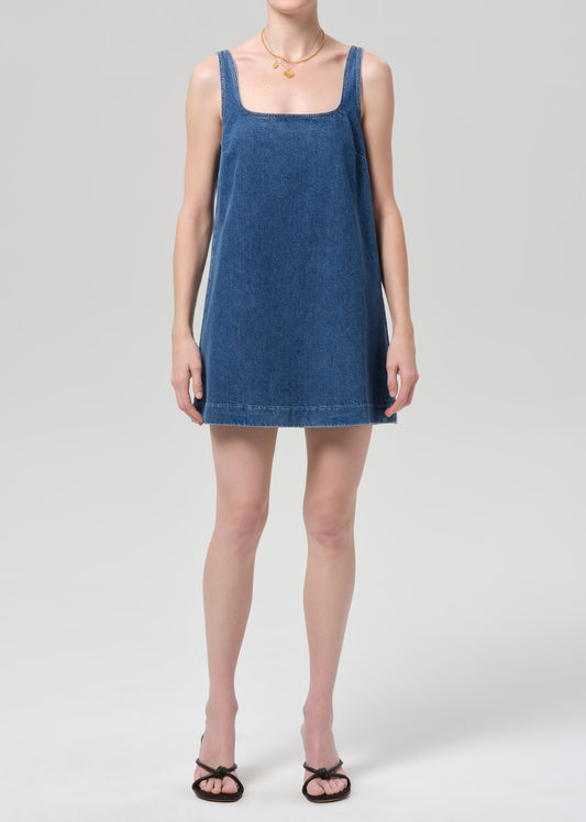Woman wearing a blue denim dress on a plain background
