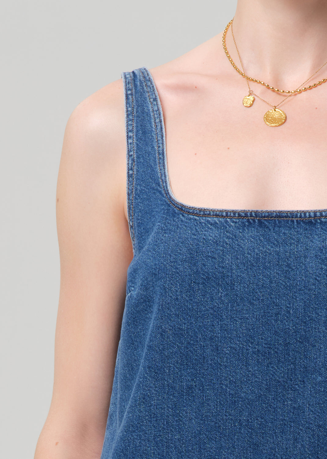 Blue denim dress worn by a person on a gray background