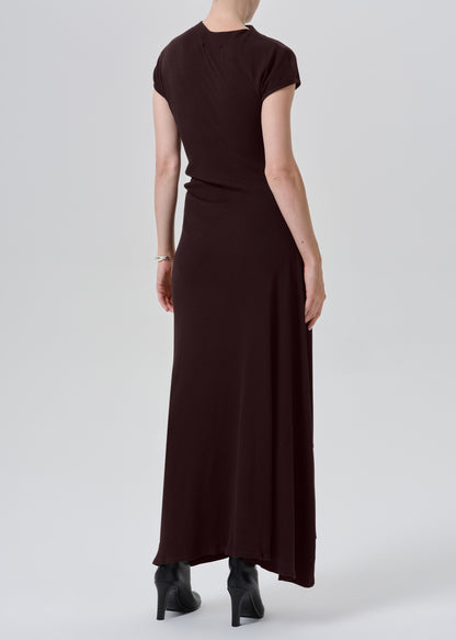 A woman shown from the back wearing a dark brown short-sleeve maxi dress and black pointed-toe heels against a grey background.