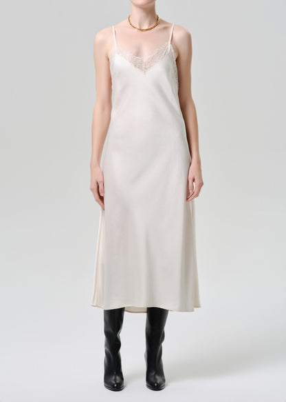 Person wearing a white slip dress with black boots on a grey background