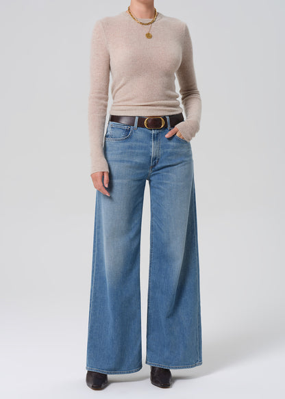 Person wearing a beige sweater and blue jeans on a white background