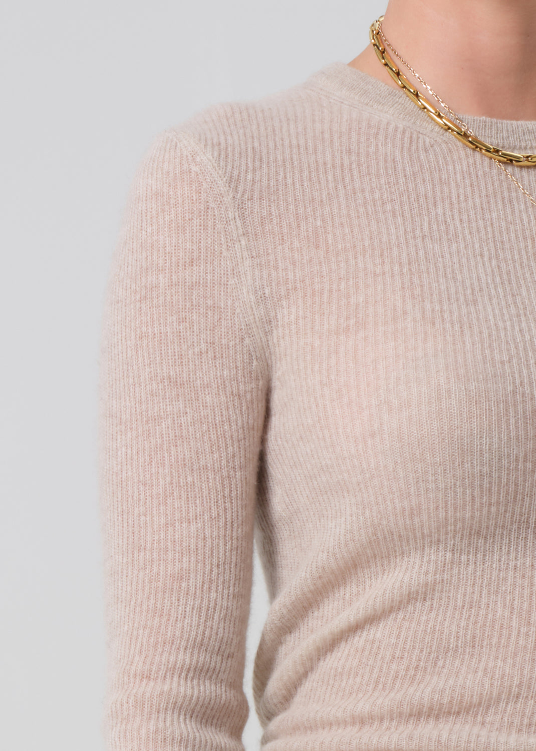 Beige sweater worn by a person on a light gray background