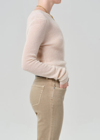 Person wearing a light cream sweater and beige pants on a plain background