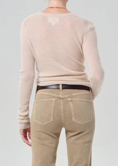 Person wearing a beige sweater and tan pants on a plain background