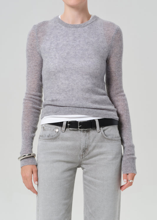 Person wearing a gray sweater and light gray jeans on a plain background