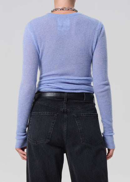 Person wearing a light blue sweater and dark jeans on a plain background