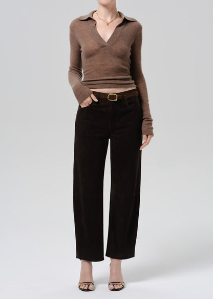 A model wearing a brown knit collared long-sleeve top and dark brown wide-leg cropped pants with a gold belt buckle, styled with beige flat sandals against a grey background.