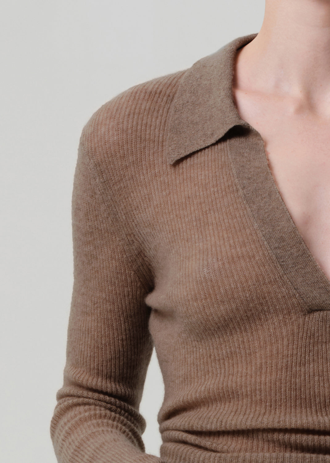Brown ribbed sweater worn by a person on a plain background