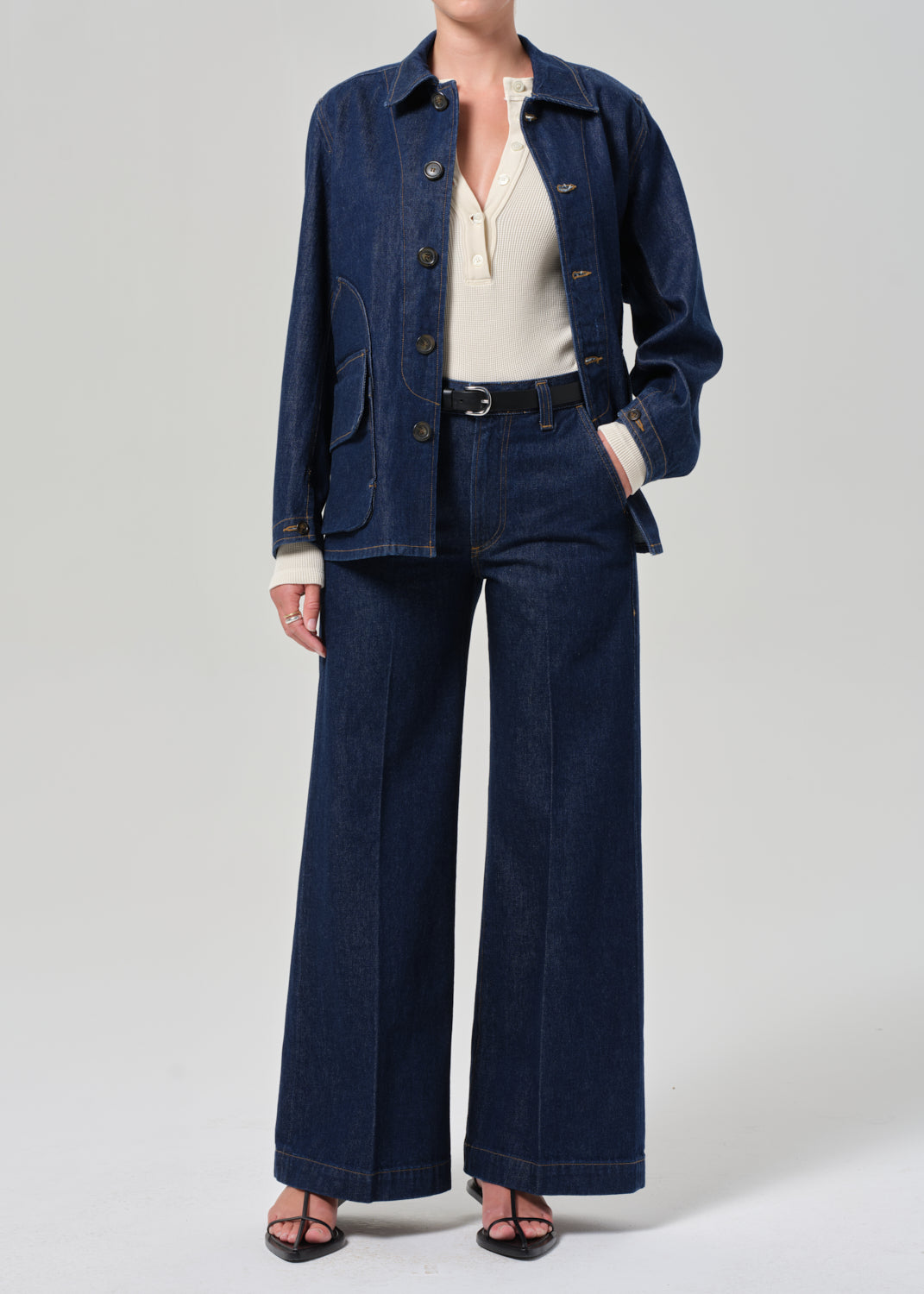 Person wearing a denim jacket and pants on a plain background