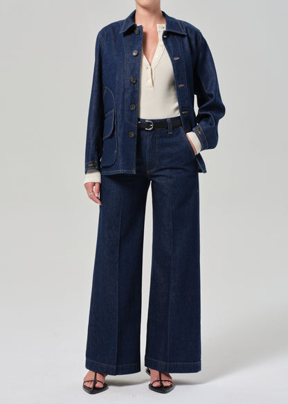 Person wearing a denim jacket and pants on a plain background