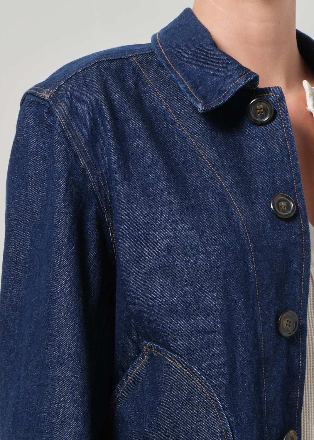 Close-up of a blue denim jacket with buttons on a gray background