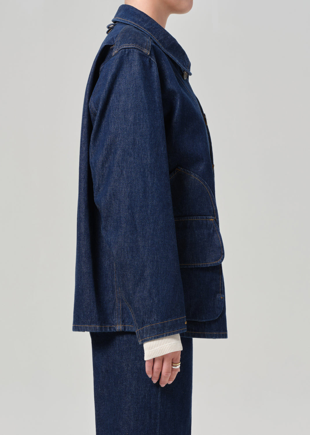 Person wearing a dark blue denim jacket on a light gray background