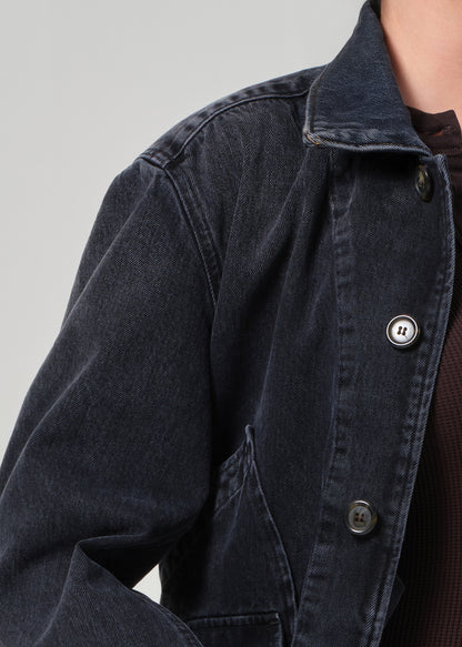 Close-up of a dark denim jacket with buttons on a plain background