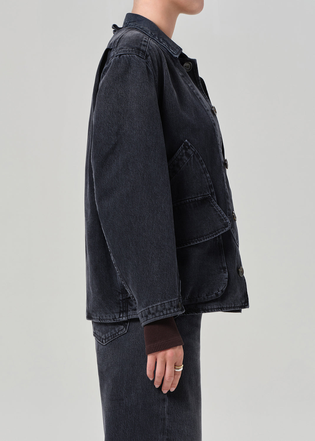 Person wearing a dark denim jacket on a light gray background