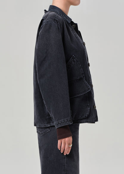 Person wearing a dark denim jacket on a light gray background