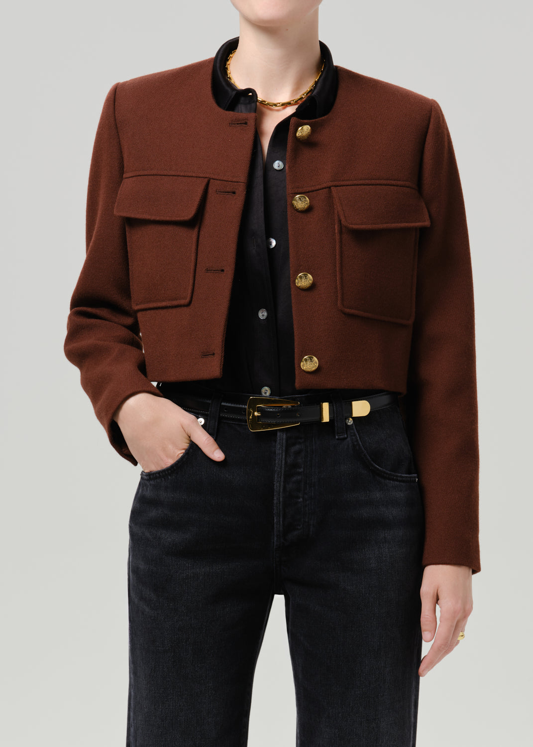 Close-up of a brown tailored cropped jacket on a grey background