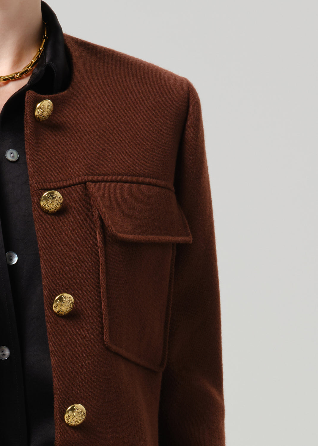 Close-up of a brown tailored cropped jacket on a grey background