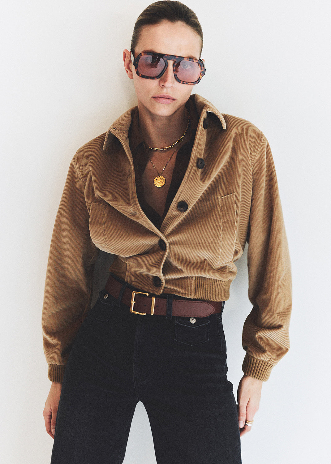 Person wearing a brown corduroy jacket and sunglasses against a white background