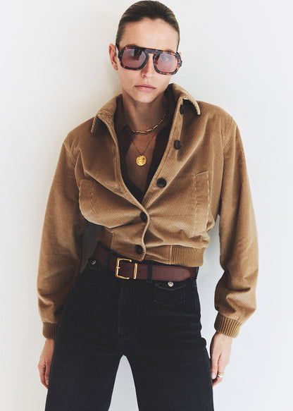 Person wearing a brown corduroy jacket and sunglasses against a white background