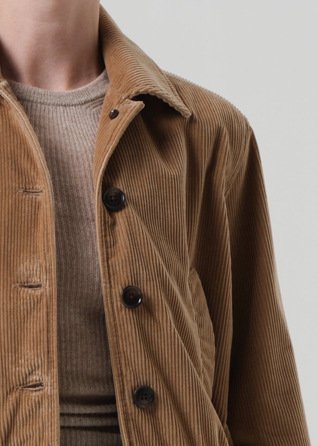 Brown corduroy jacket with black buttons on a neutral background