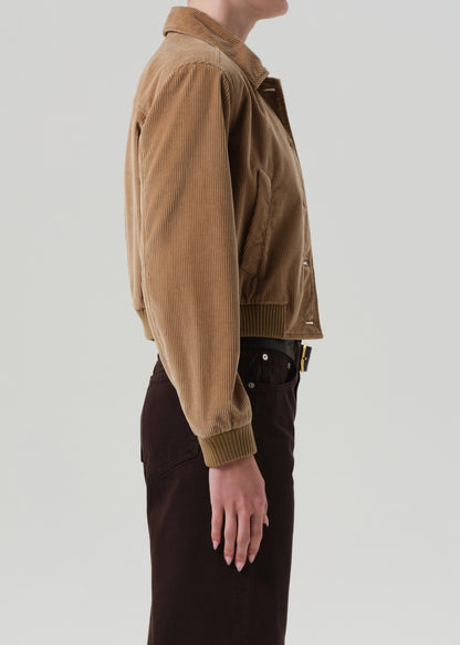 Person wearing a brown corduroy jacket on a plain background