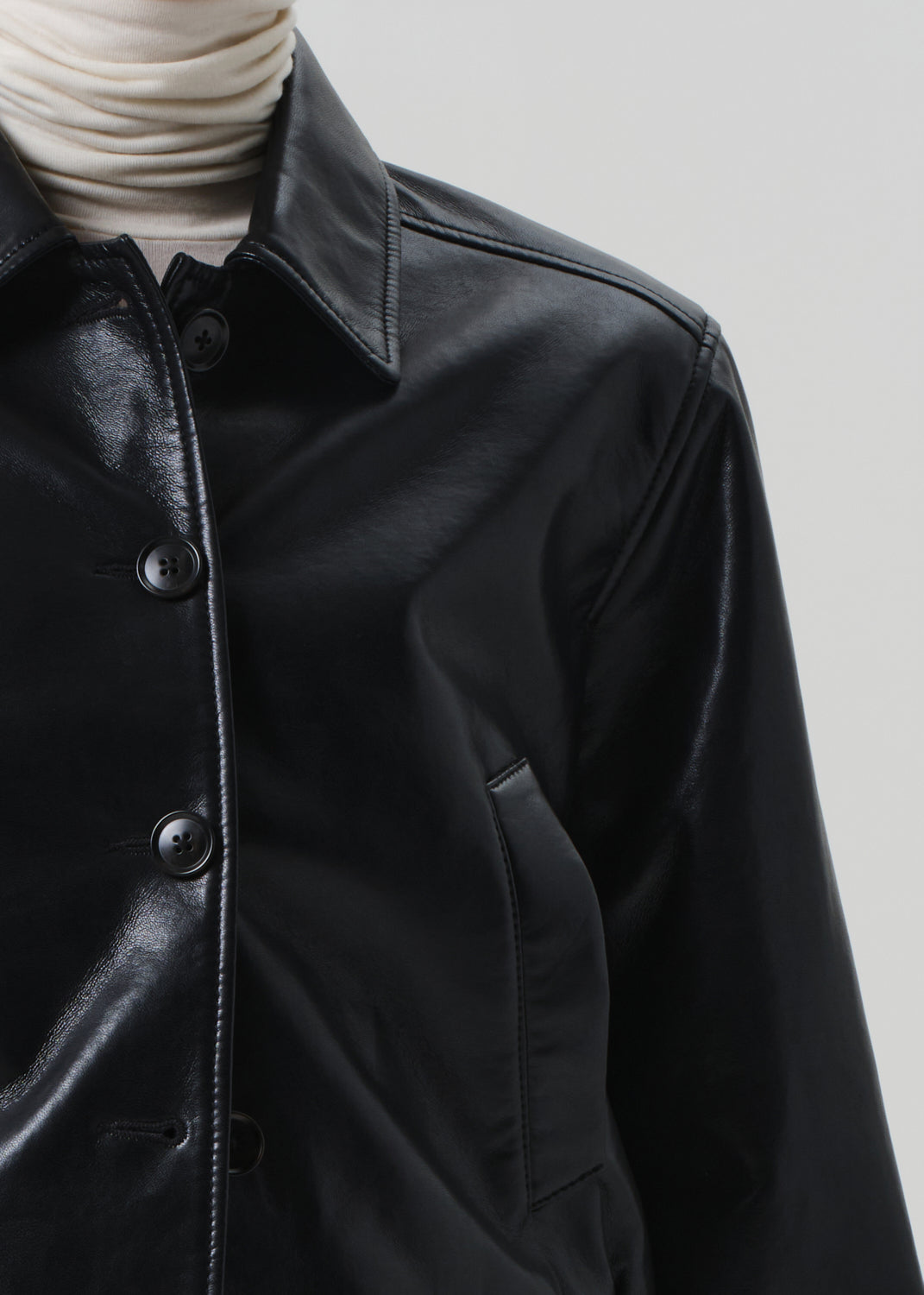 Black leather jacket with button details on a neutral background