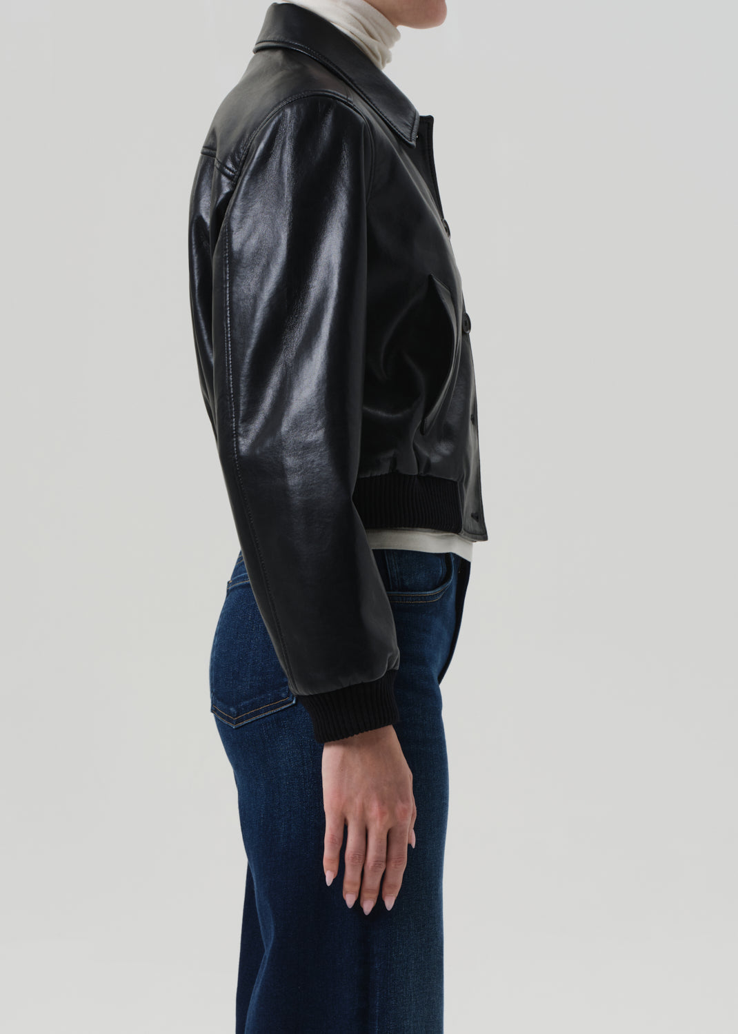 Person wearing a black leather jacket on a light gray background