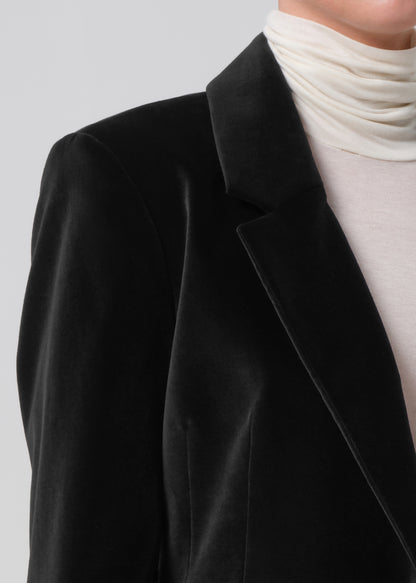 Black blazer worn over a white turtleneck on a plain background