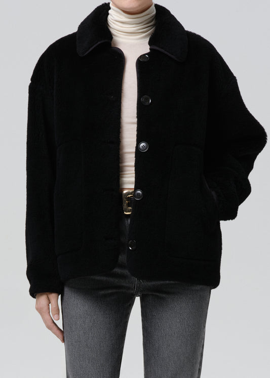 Person wearing a black coat with a grey background