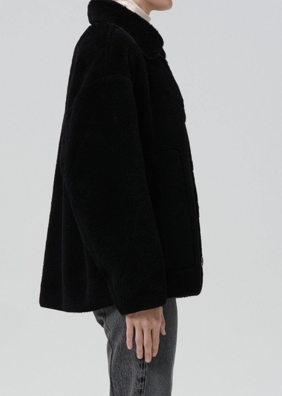 Black coat worn by a person on a grey background