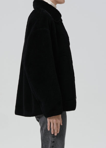 Black coat worn by a person on a grey background