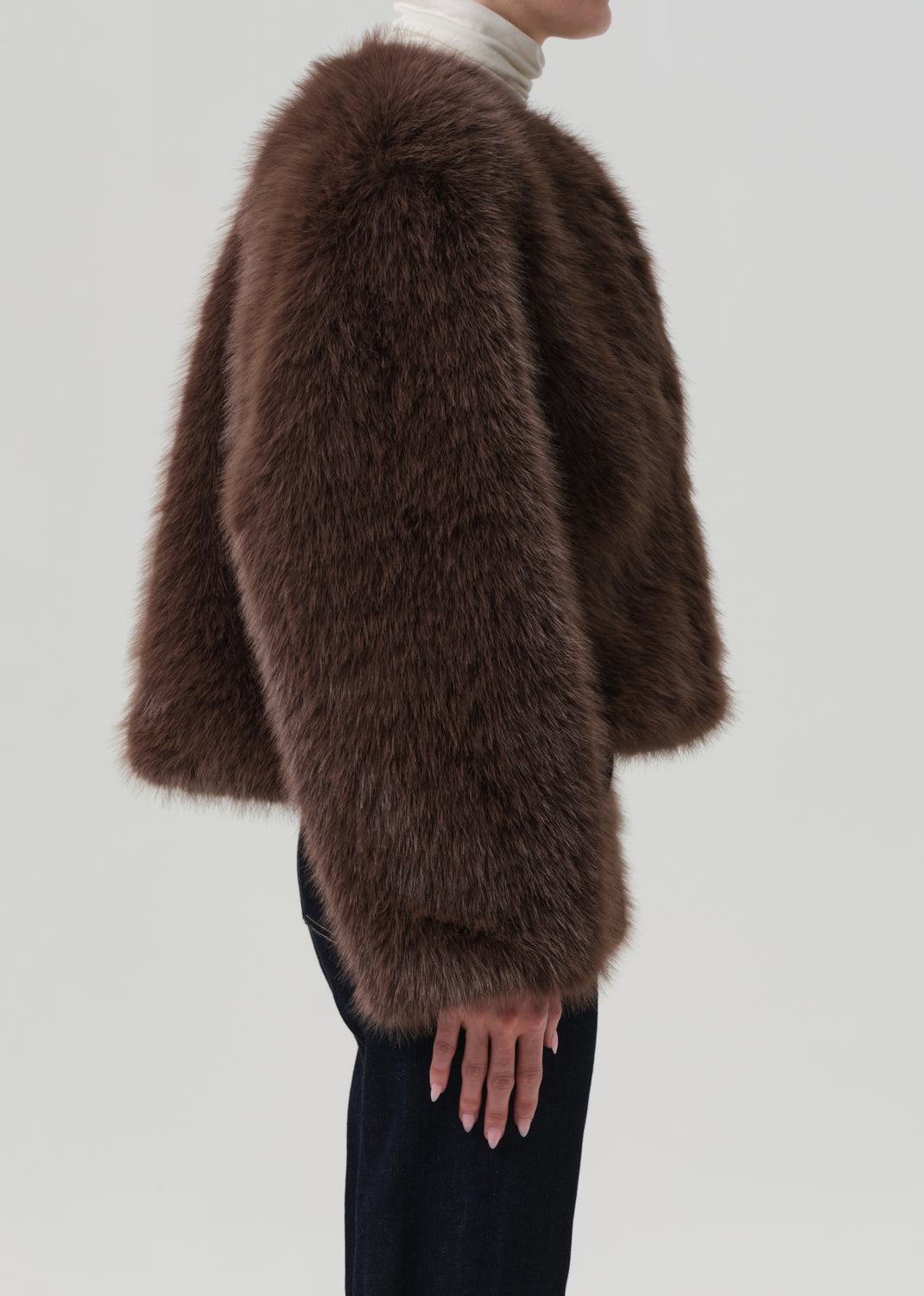 Brown fur coat worn by a person on a light gray background