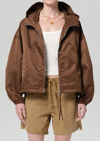 Person wearing a brown jacket and beige shorts on a plain background