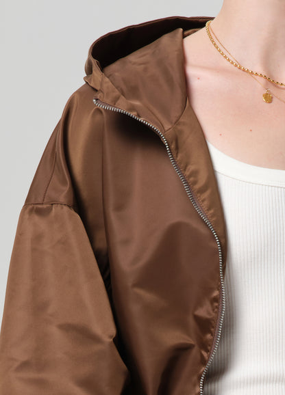 Brown jacket with a hood worn by a person against a neutral background