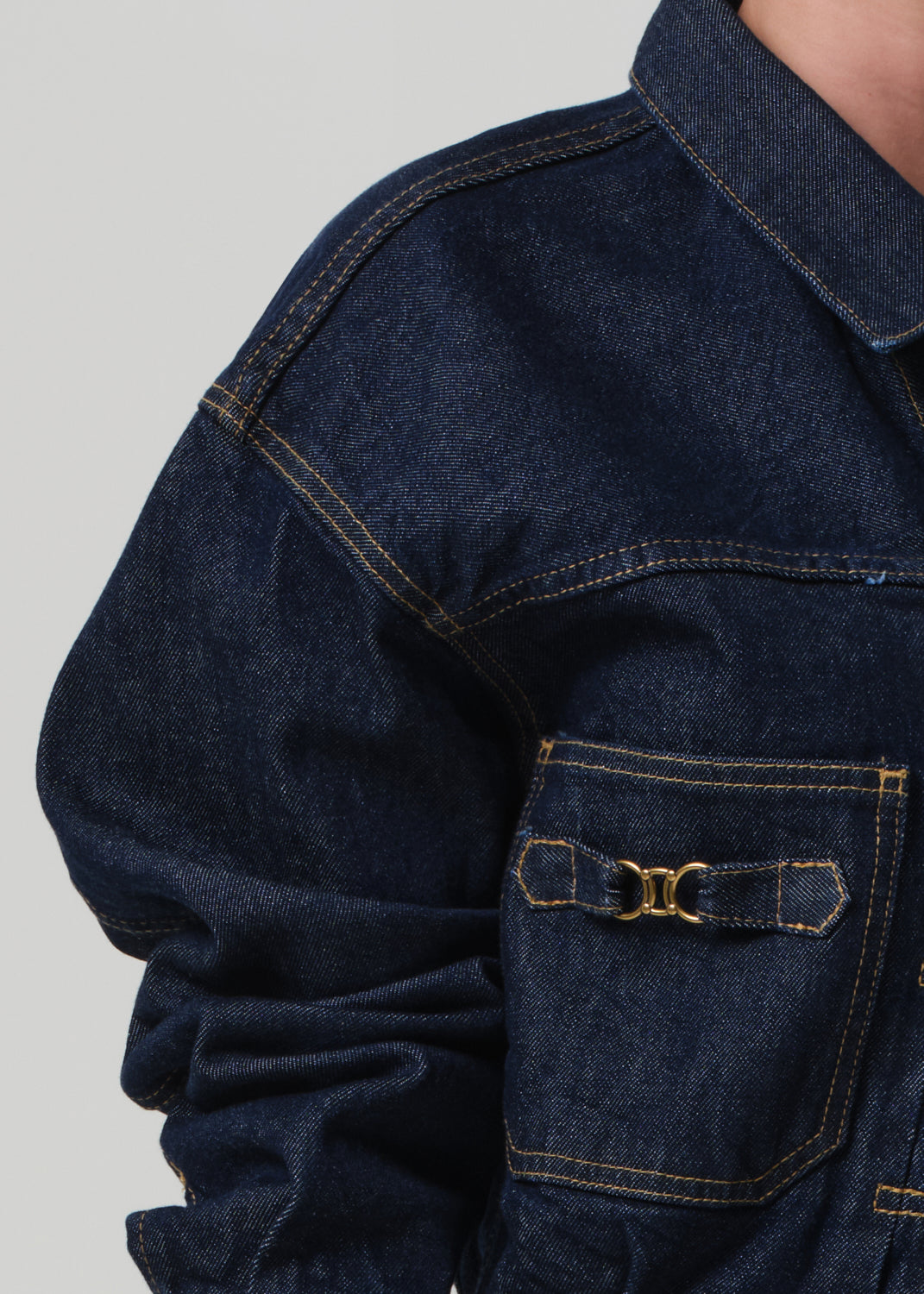 Close-up of a dark blue denim jacket with a pocket on a light gray background