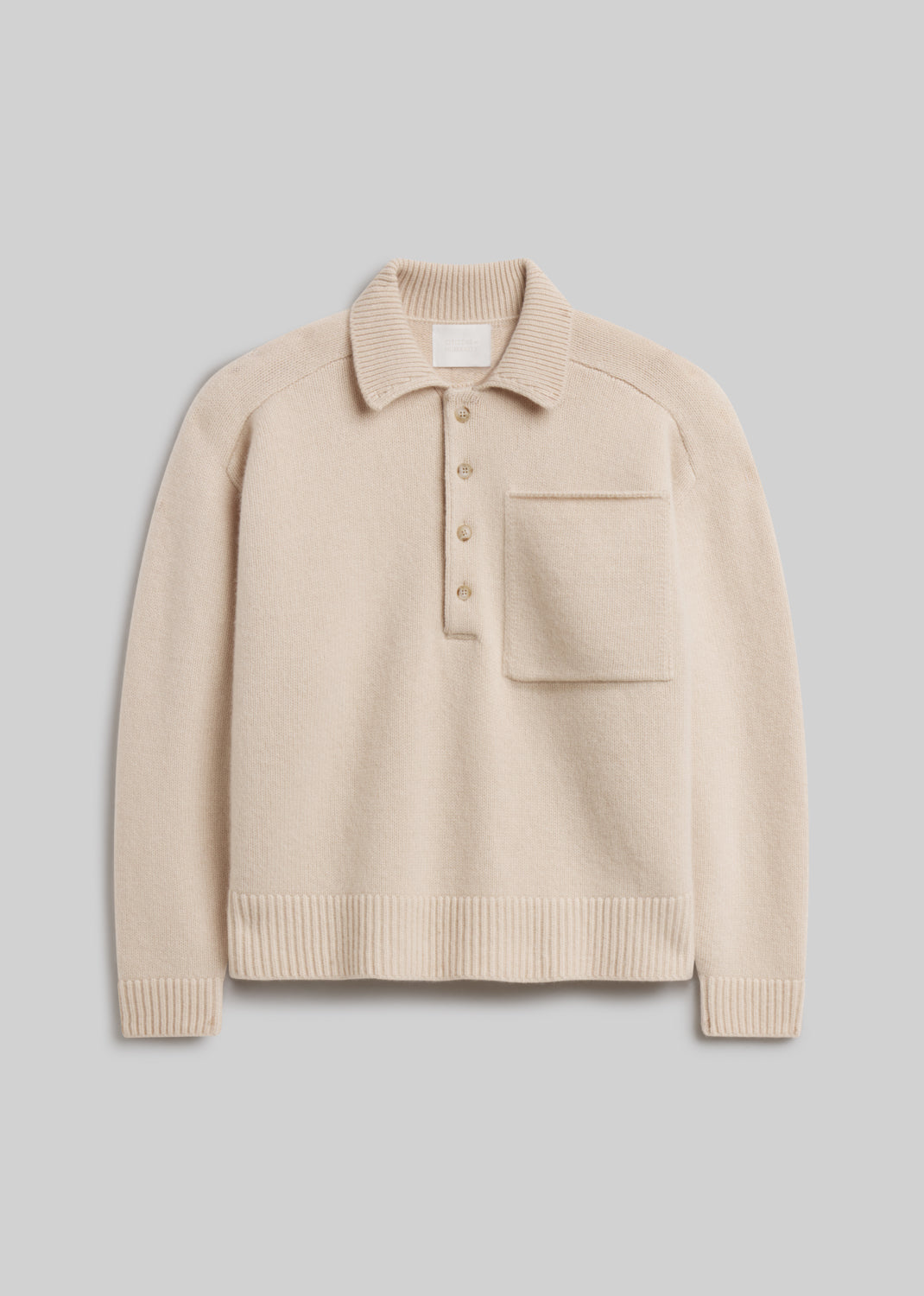 Agatha Rugby in Pillow, featuring a soft cream knit, ribbed collar, four-button placket, front chest pocket, and ribbed cuffs and hem, front view on a grey background.