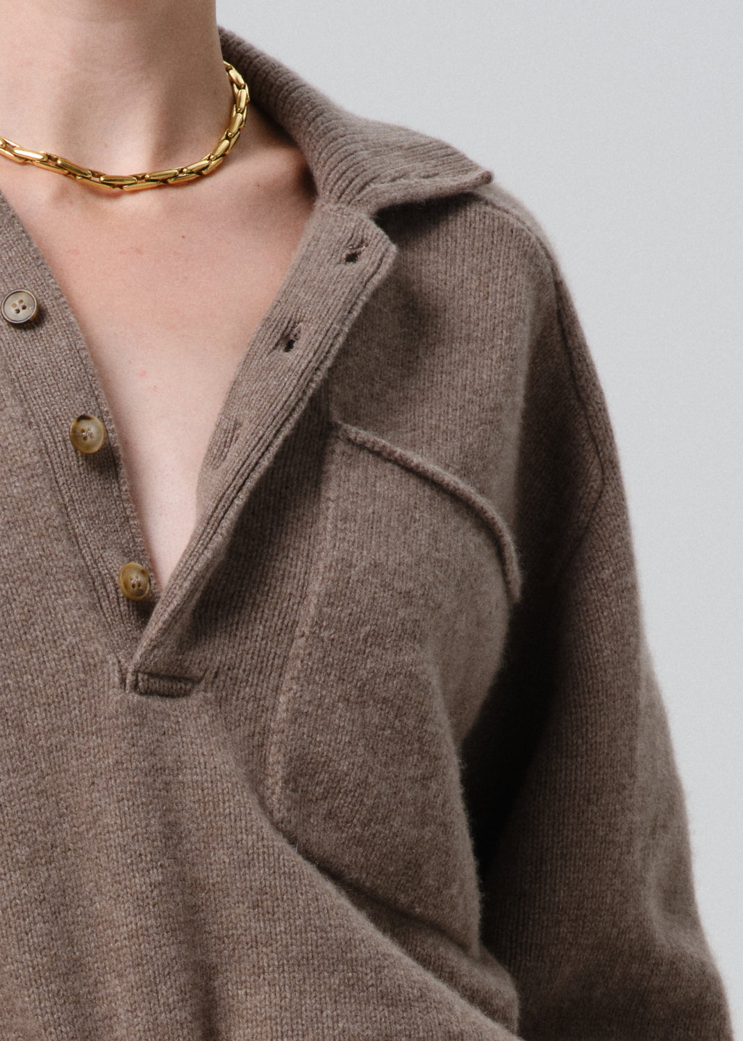 Close-up of a brown jacket with button details on a grey background