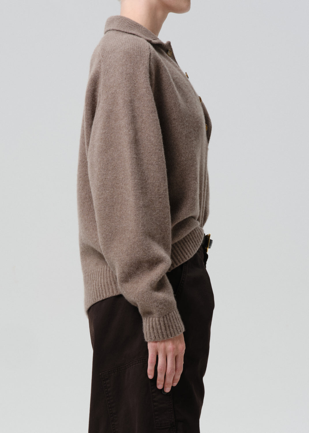 Person wearing a brown knitted sweater against a grey background