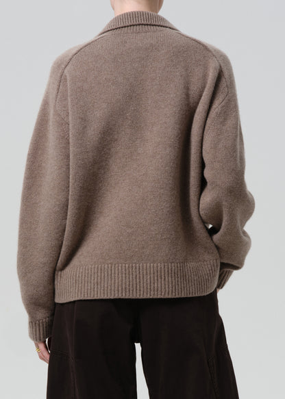 Person wearing a brown sweater against a grey background