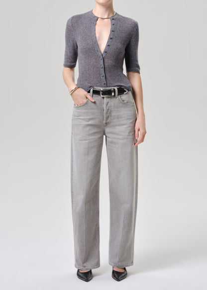 Person wearing a gray cardigan and light gray pants on a grey background.