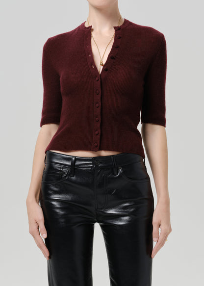 Person wearing burgundy cardigan and black pants on a grey background