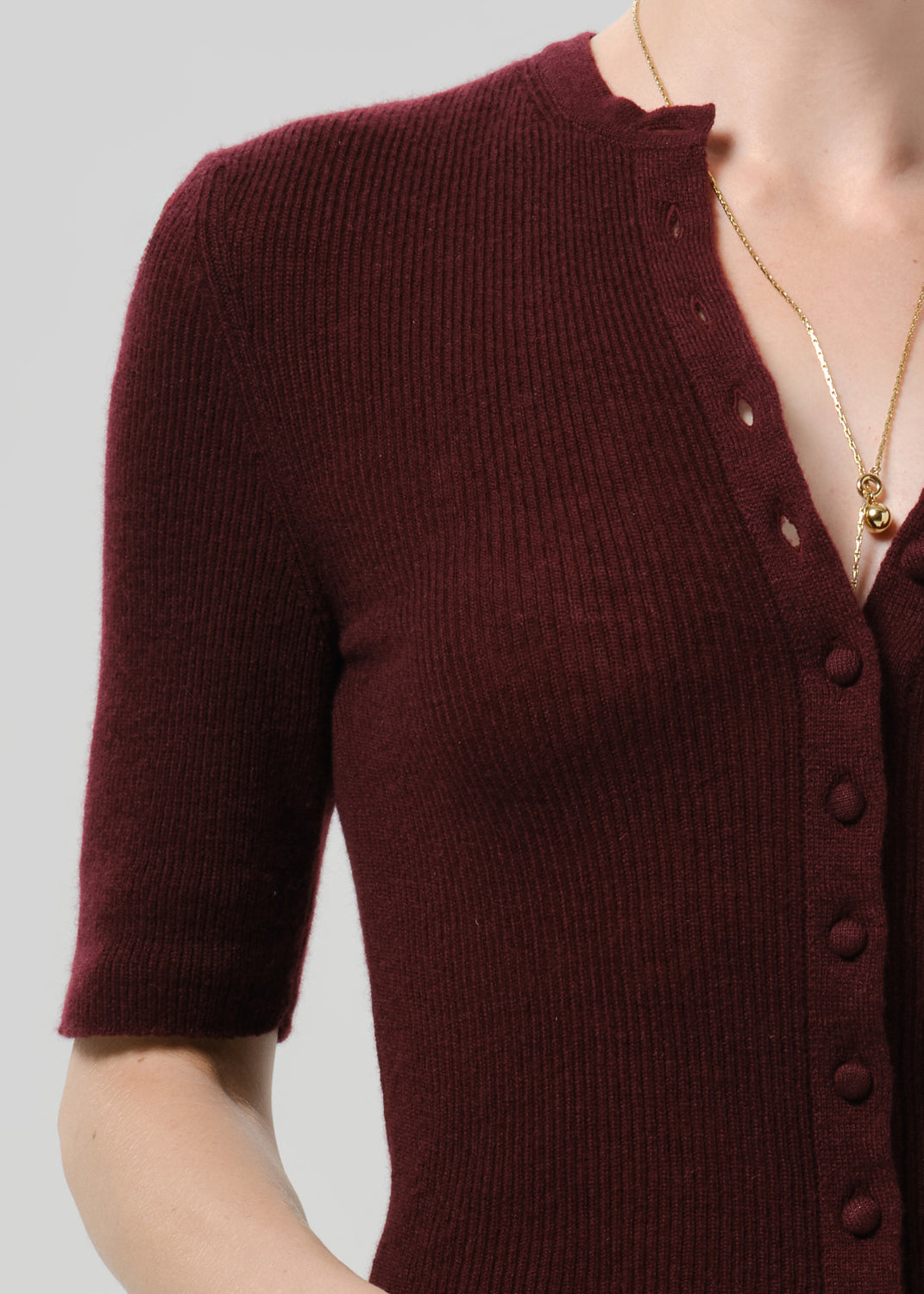 Close up shot of burgundy cardigan on a grey background