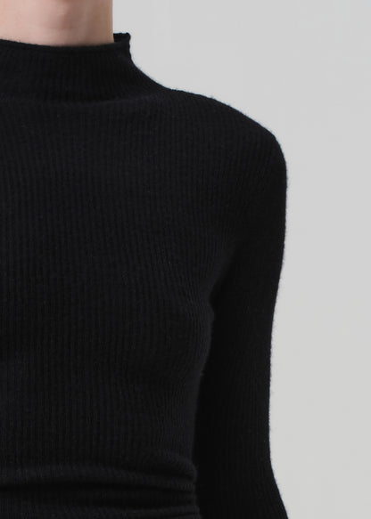 Black ribbed sweater worn by a person on a light gray background