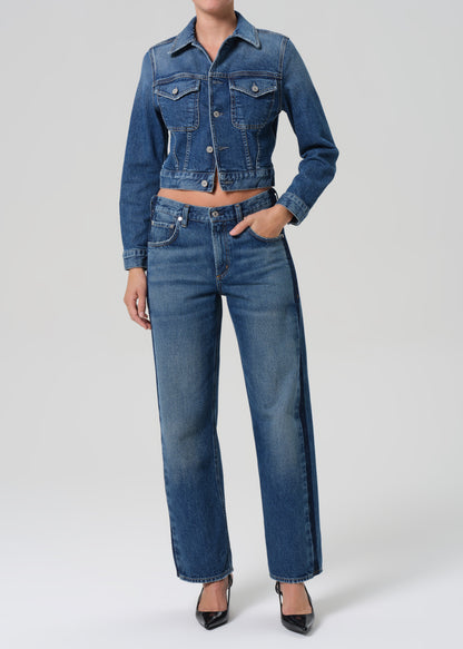 Person wearing a blue denim jacket and jeans on a white background