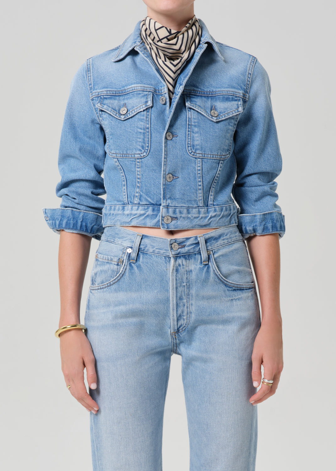 Person wearing a denim jacket and jeans on a plain background