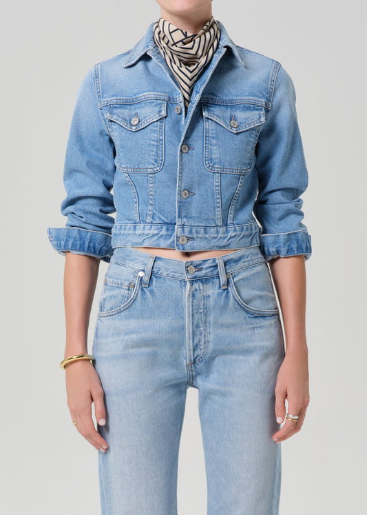 Person wearing a denim jacket and jeans on a plain background